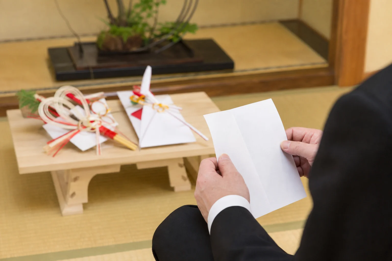 口上のメモを手元に置き、白木の台にのせた結納品を前に話す場面の写真